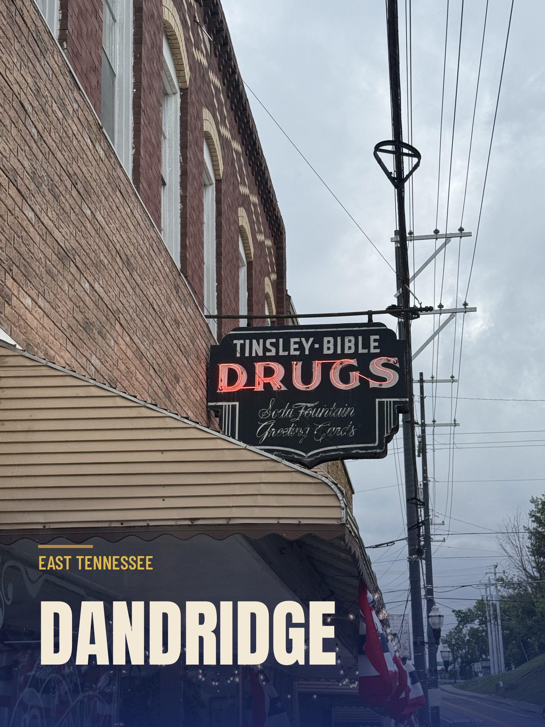 The lit Tinsley-Bible Drugs neon sign hanging over the sidewalk on Gay Street in downtown Dandridge, Tennessee.