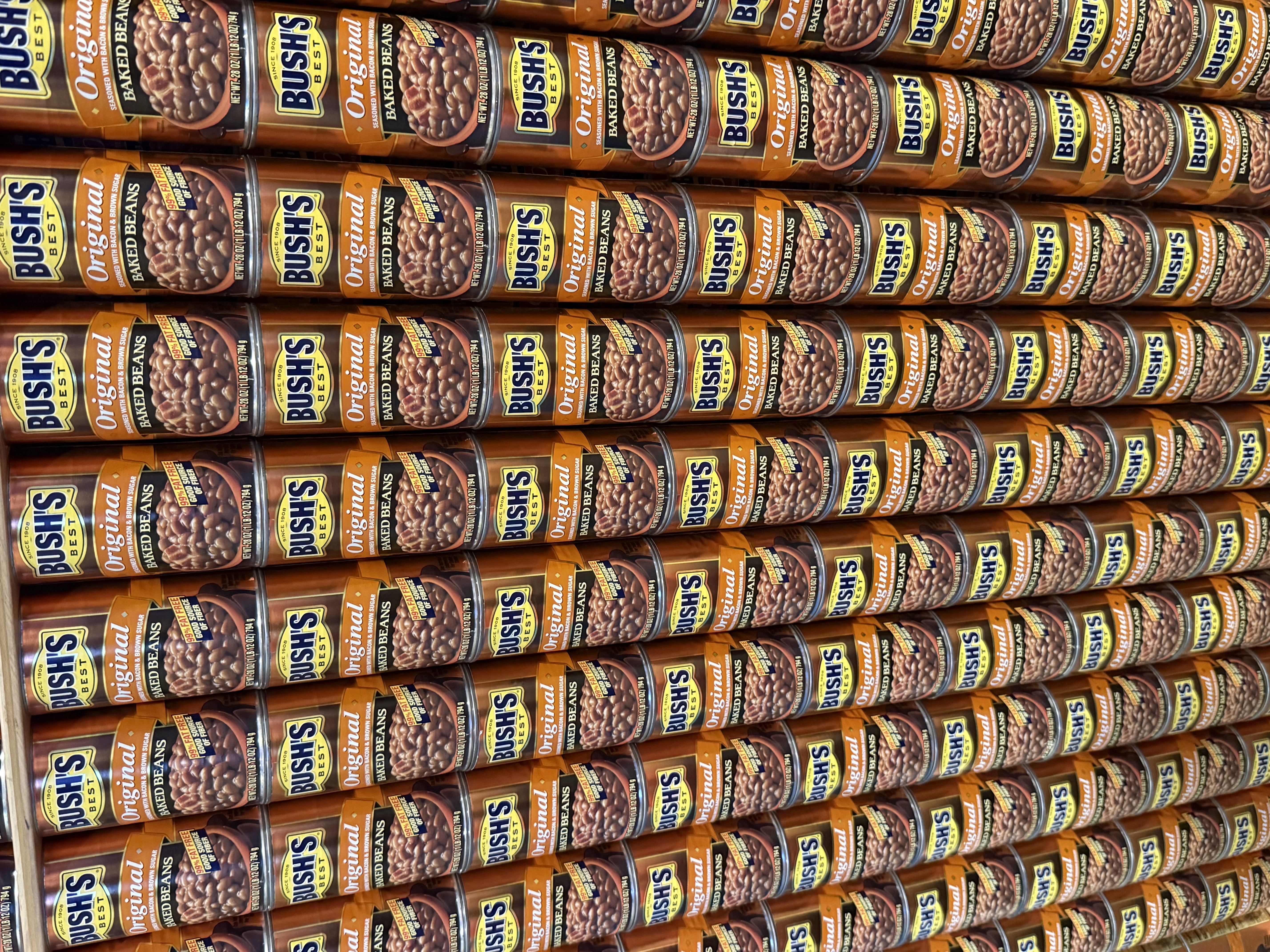 A close wall of stacked Bush's Best Original Baked Beans cans.